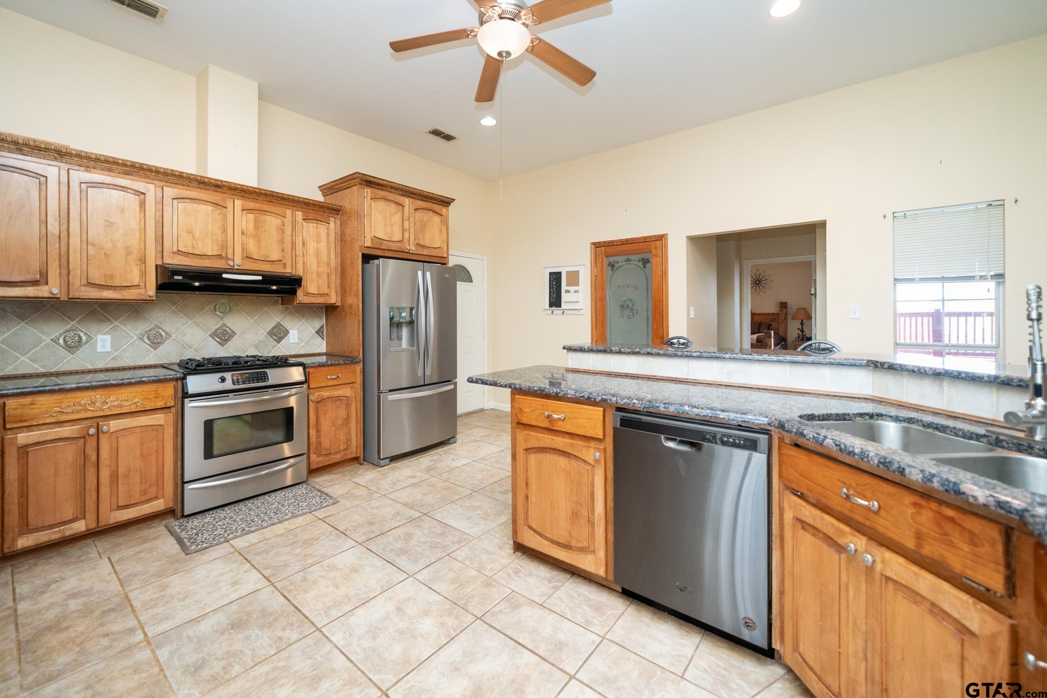 2266 Big Woods Road Longview, TX 75605 - Photo 18 of 48 a kitchen with stainless steel appliances granite countertop a stove a sink and a refrigerator