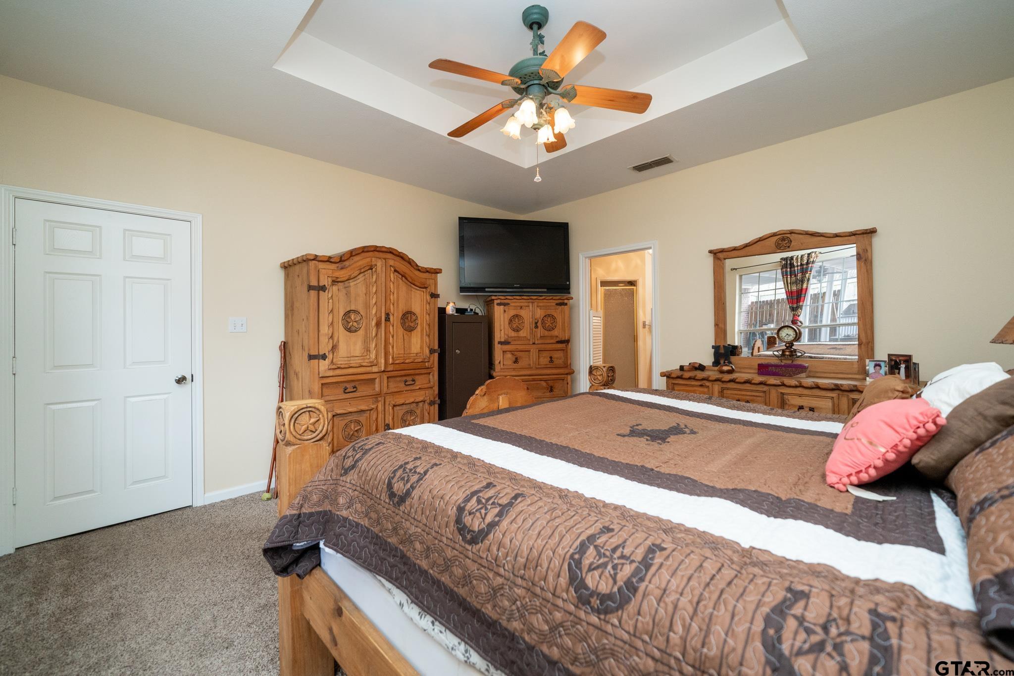 2266 Big Woods Road Longview, TX 75605 - Photo 24 of 48 a spacious bedroom with a bed and a chandelier