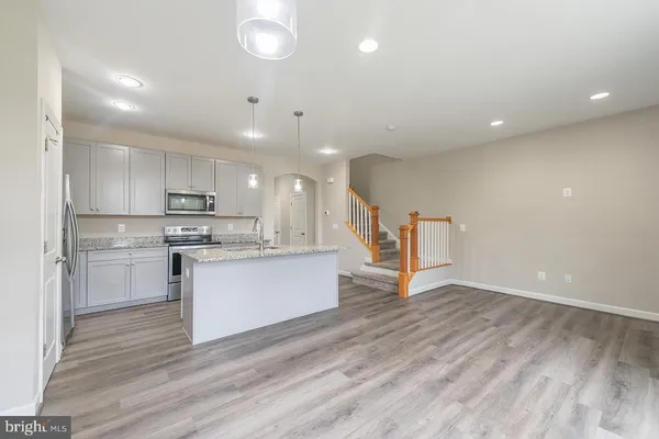 a view of kitchen with center island stainless steel appliances wooden floor and window