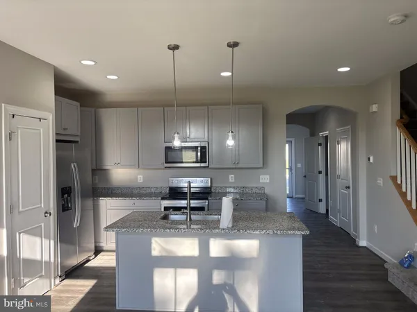 a kitchen with kitchen island granite countertop a sink a stove and a refrigerator