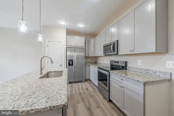 a kitchen with kitchen island granite countertop a sink stainless steel appliances and cabinets