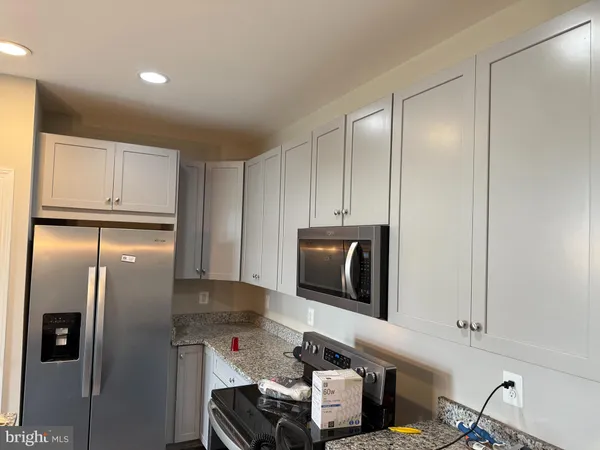 a kitchen with stainless steel appliances granite countertop a refrigerator a stove and a microwave with wooden floor