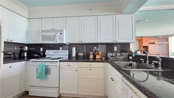 a kitchen with counter top space a sink a window and living room