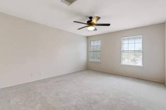 an empty room with windows and fan