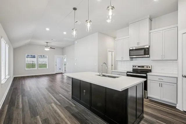 a kitchen with a sink center island wooden floor and stainless steel appliances