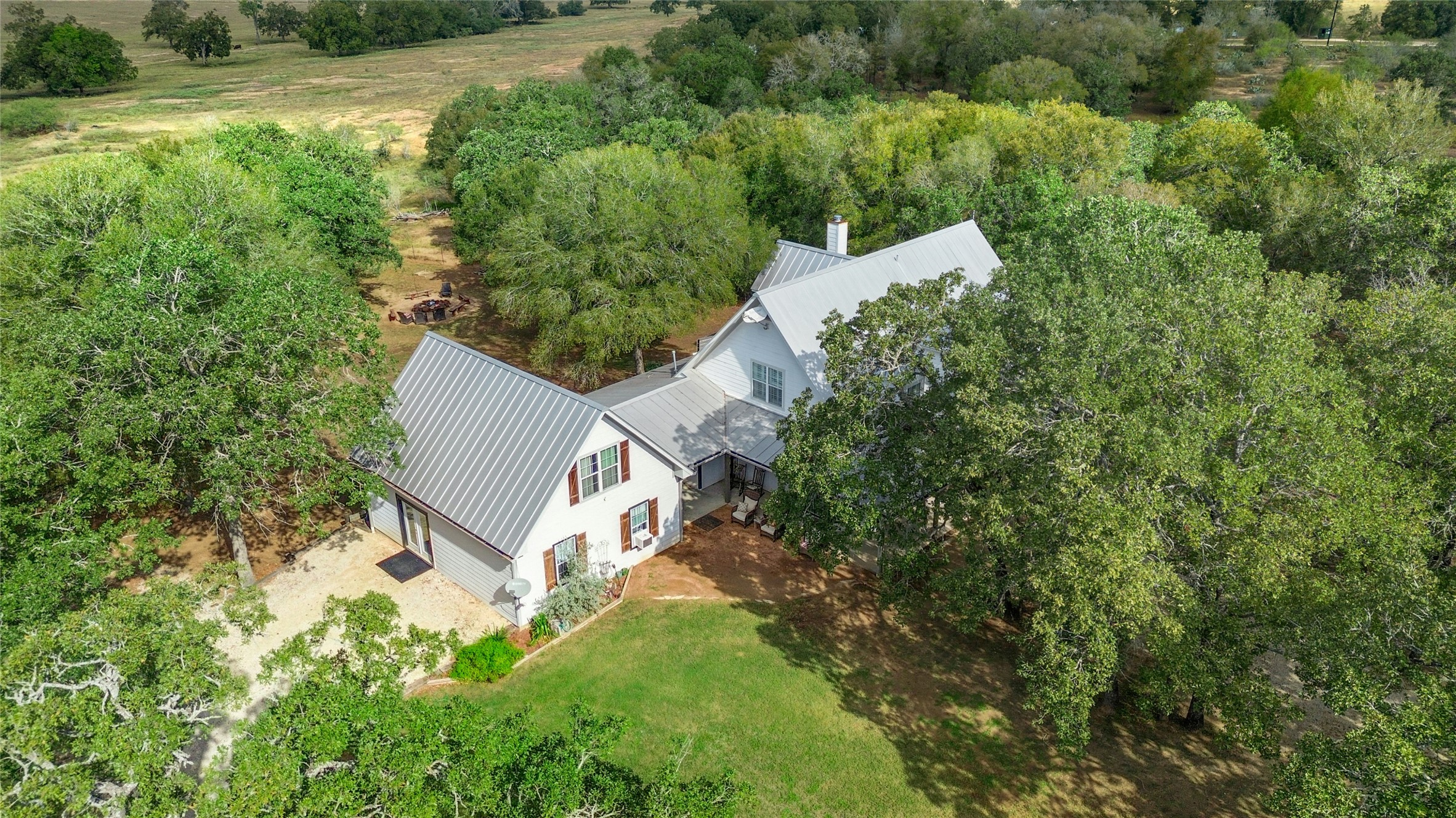 Aerial view of property and surrounding area with a tree filled landscape
