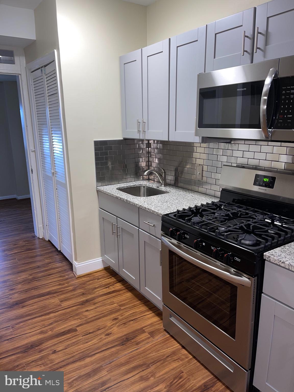 2210 Nicholson Street Southeast, Unit 3 Washington, DC 20020 - Photo 8 of 25 a kitchen with stainless steel appliances a stove a microwave a sink and cabinets