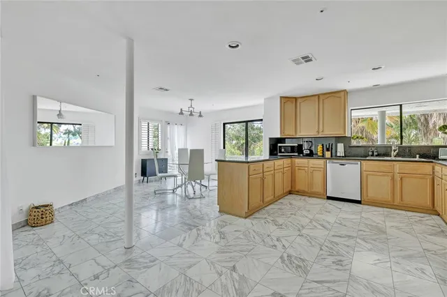 a large kitchen with kitchen island granite countertop a stove a sink a counter top space and cabinets