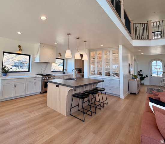 3626 Riverstone Road Mapleton, UT 84664 - Photo 13 of 58 Dual tone kitchen featuring a kitchen breakfast bar, stainless steel range, a kitchen island with sink, hanging light fixtures, and light wood finished floors