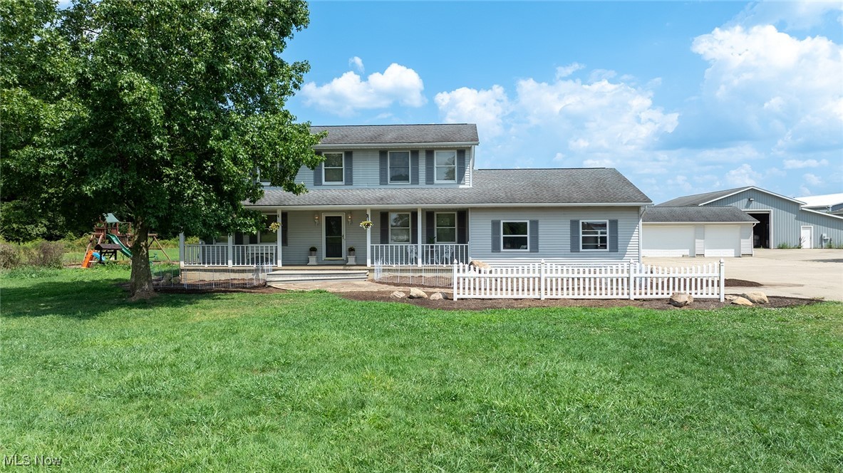 7686 Peck Road Ravenna, OH 44266 - Photo 1 of 2 View of front facade with a porch, a garage, concrete driveway, a playground, and roof with shingles