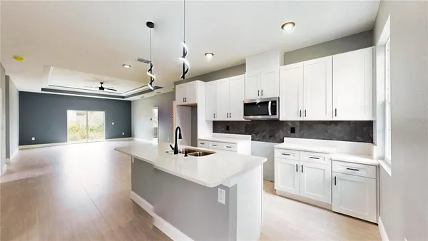 a kitchen with kitchen island a white counter top space a sink a stove and a window