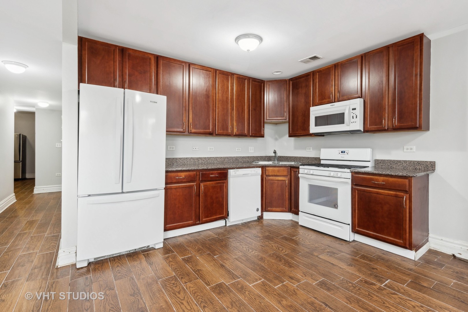 2256 West Adams Street, Unit G Chicago, IL 60612 - Photo 4 of 11 a kitchen with granite countertop wooden cabinets a stove a sink and a refrigerator