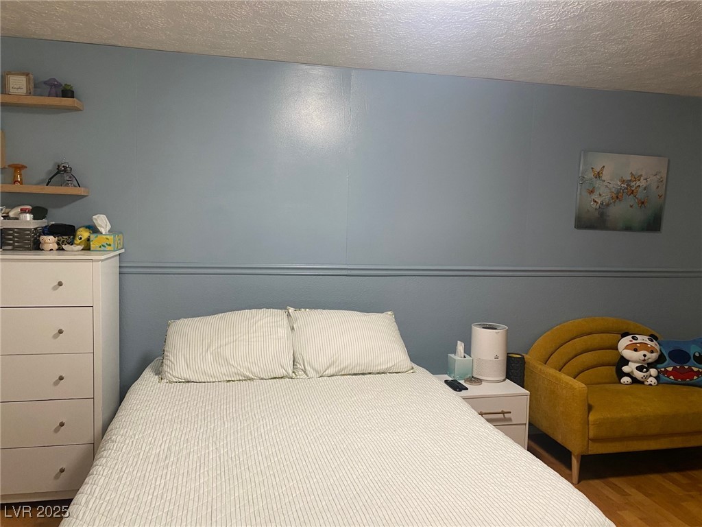 735 Canyon Street Ely, NV 89301 - Photo 8 of 20 Downstairs Bedroom featuring a textured ceiling and wood finished floors