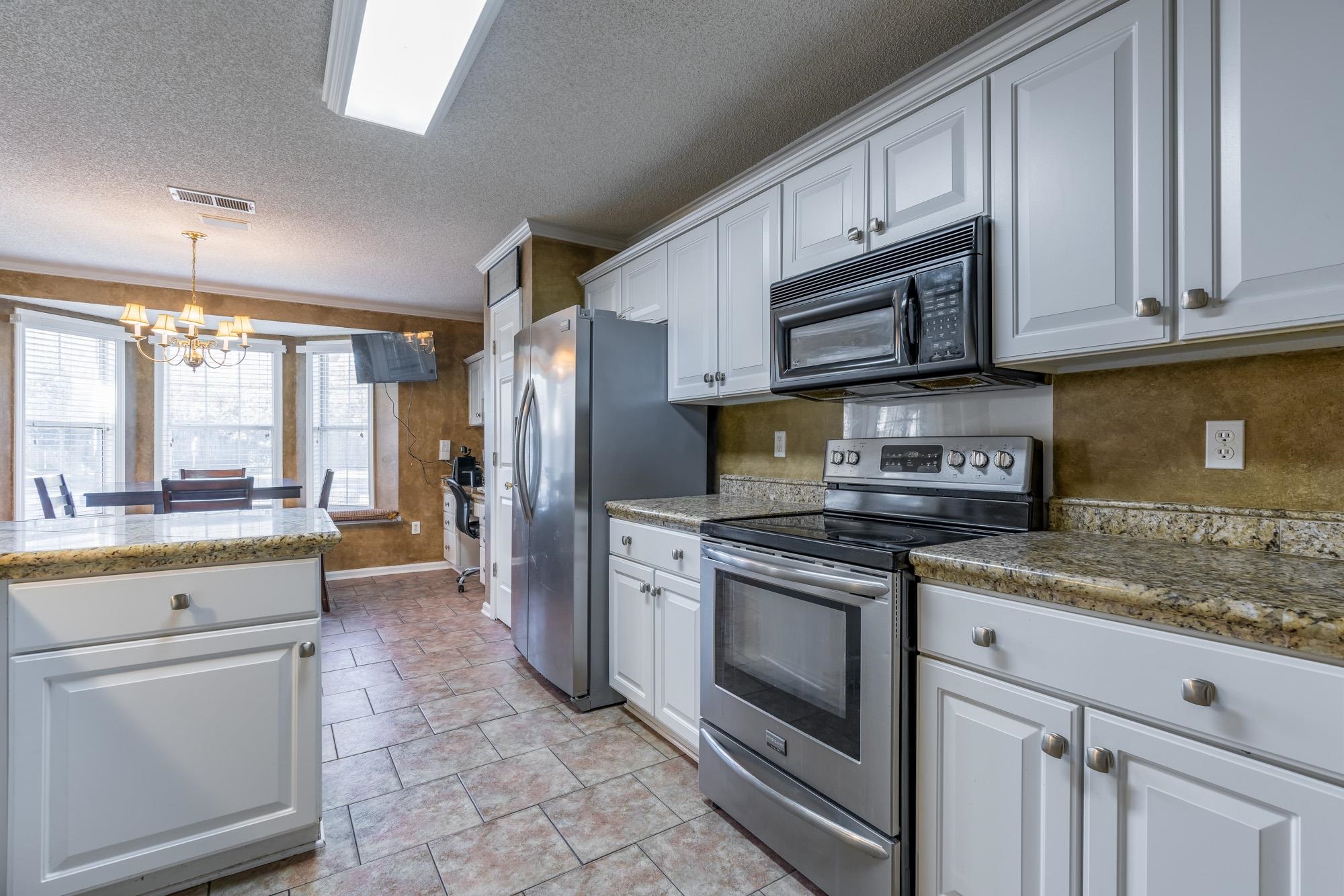 8599 Brer Fox Cove Memphis, TN 38018 - Photo 11 of 25 a kitchen with stainless steel appliances granite countertop a stove a sink and a refrigerator