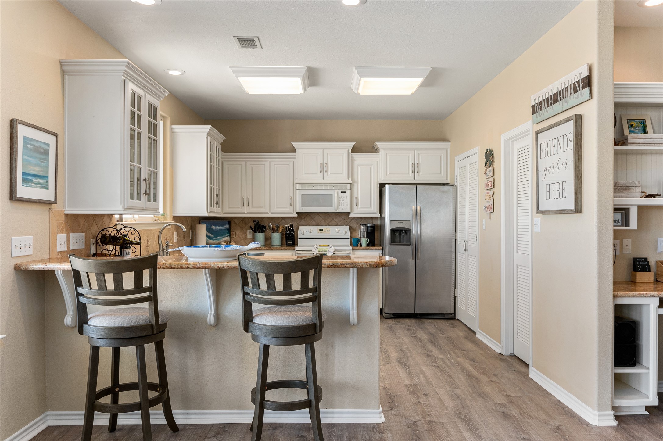 200 Mobile Crystal Beach, TX 77650 - Photo 15 of 49 a kitchen with stainless steel appliances a refrigerator a stove a sink dishwasher and white cabinets with wooden floor
