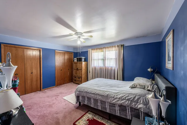 a bedroom with a bed a chandelier and dresser