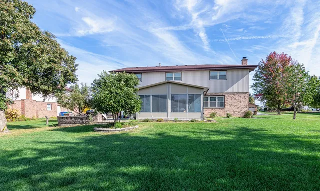a view of a house with a big yard potted plants and large tree