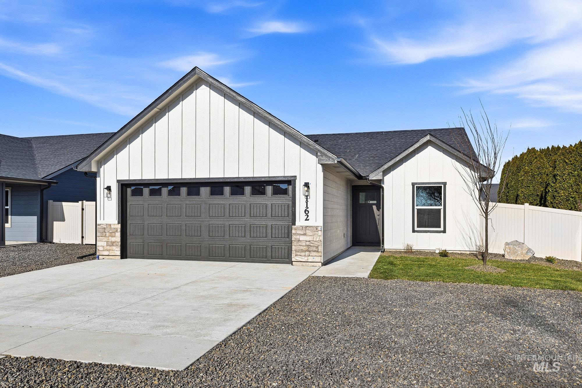 Modern farmhouse style home with board and batten siding, roof with shingles, driveway, and stone siding