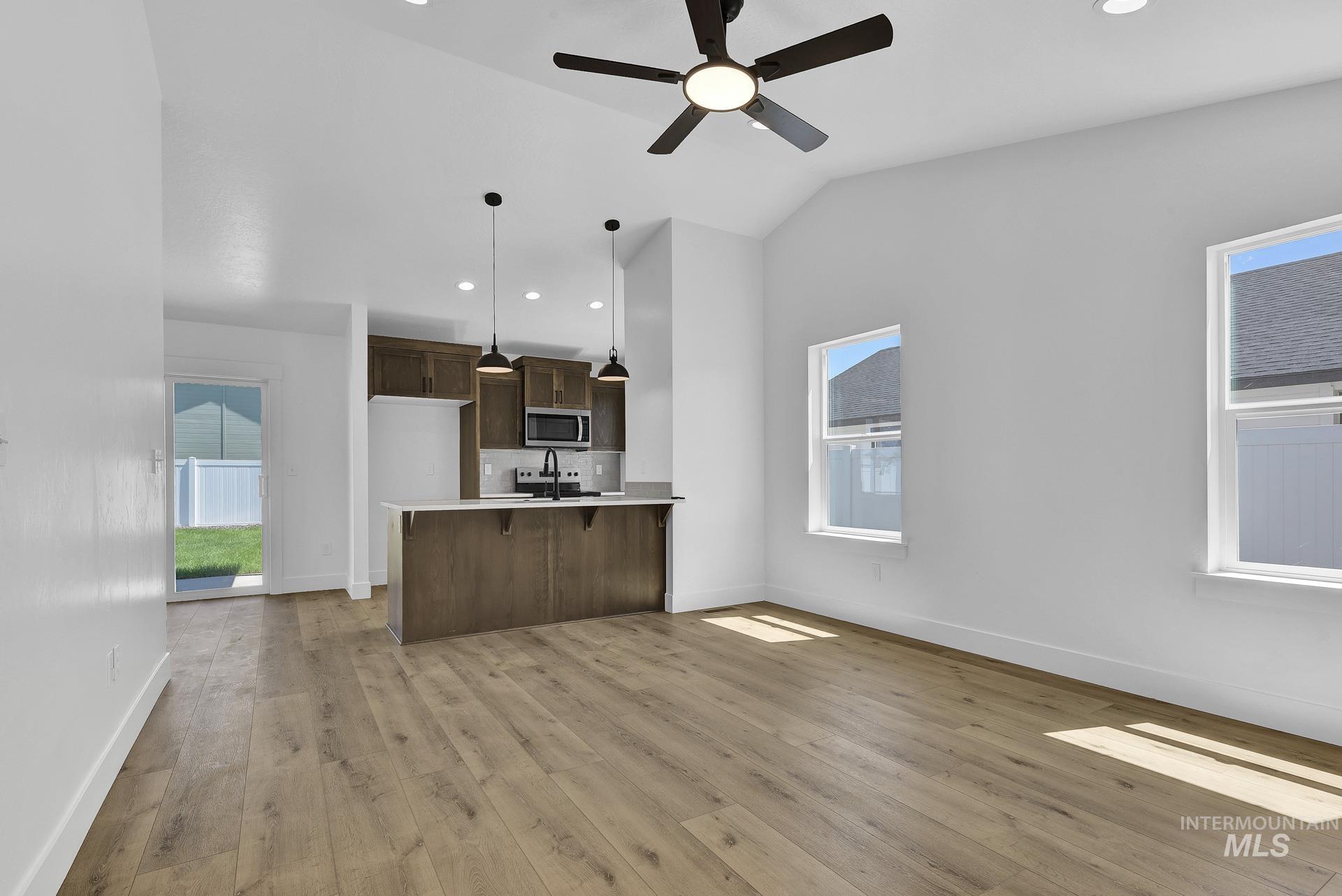 1162 Velvet Loop Wilder, ID 83676 - Photo 5 of 31 Kitchen featuring light countertops, dark brown cabinets, a kitchen breakfast bar, recessed lighting, and light wood-type flooring