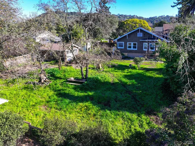 a view of a big house with a big yard and large trees
