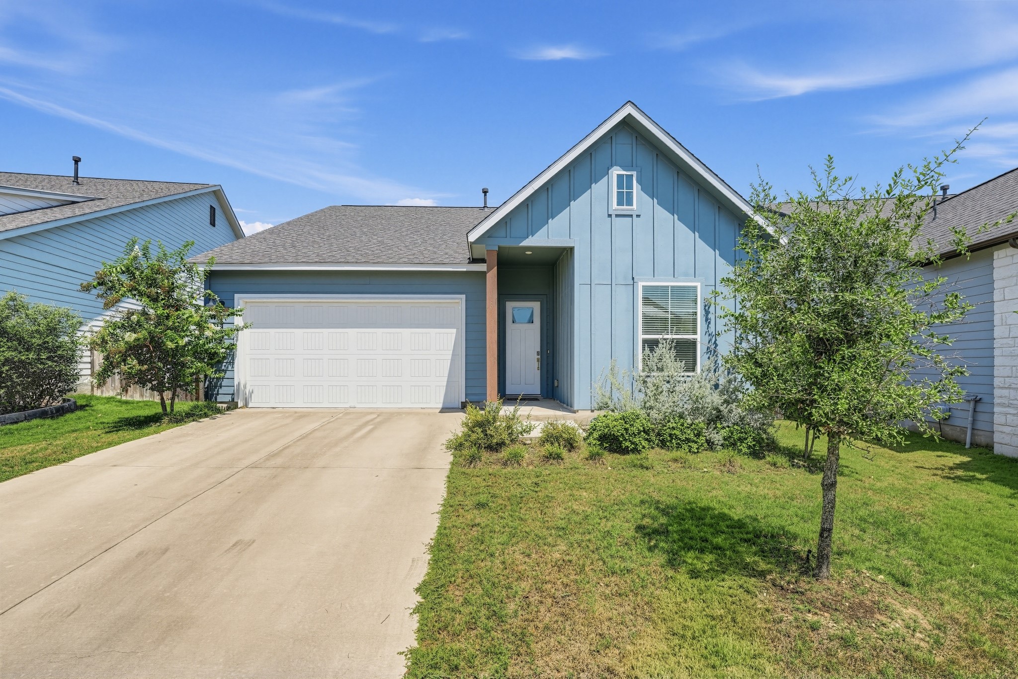 145 Brooks Ranchi Drive Kyle, TX 78640 - Photo 2 of 40 A classic concrete driveway leads to this modern two-car garage under pitched gables.