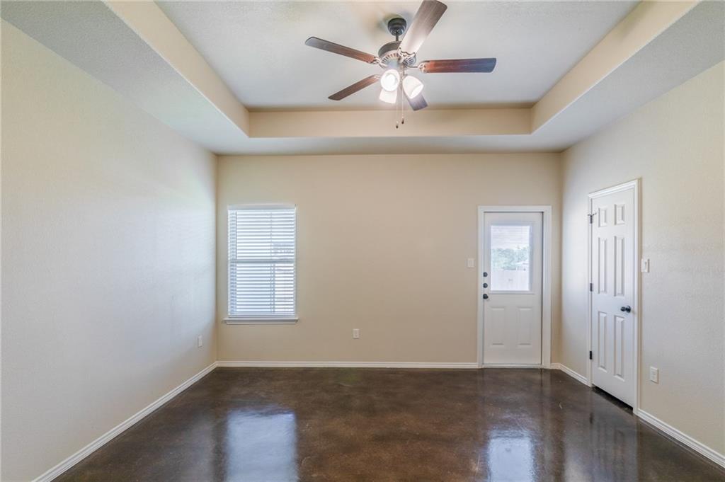 153 Samuel Drive, Unit B Buda, TX 78610 - Photo 14 of 28 an empty room with wooden floor chandelier fan and windows