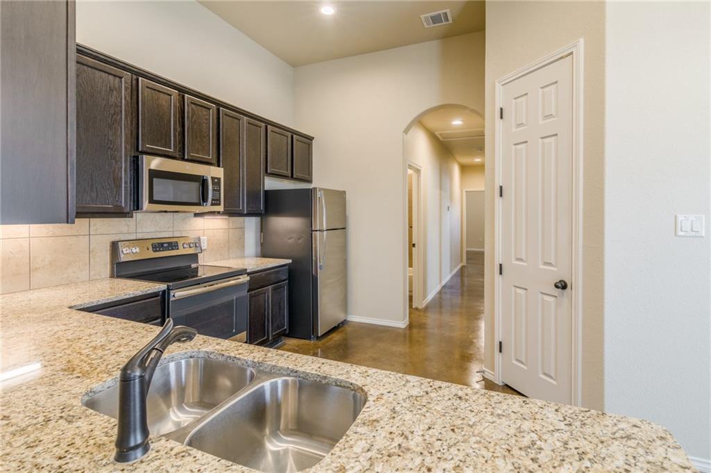 153 Samuel Drive, Unit B Buda, TX 78610 - Photo 7 of 28 a kitchen with granite countertop a sink cabinets and stainless steel appliances