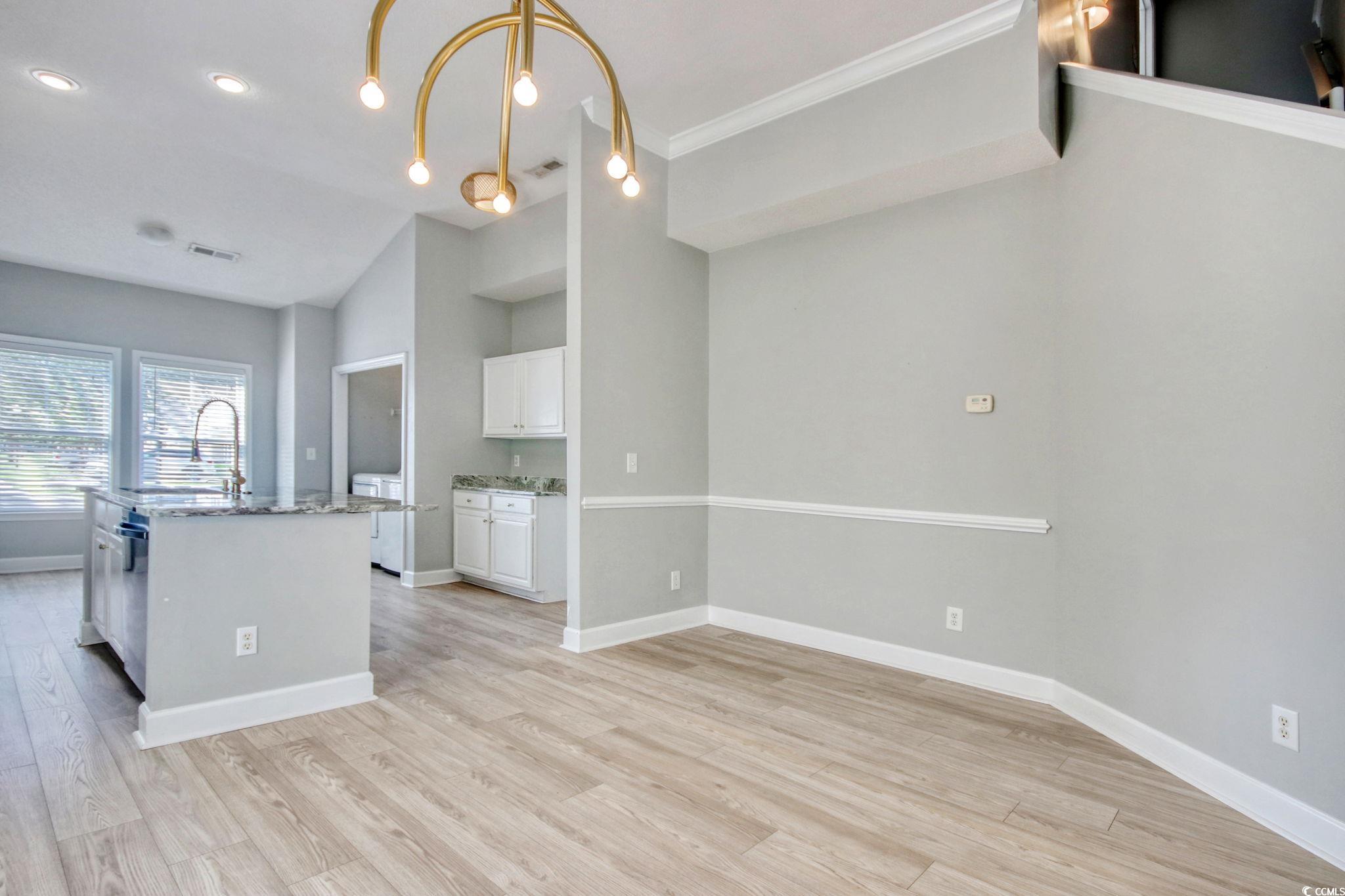 112 Coldstream Cove Loop, Unit 306 Murrells Inlet, SC 29576 - Photo 8 of 32 Kitchen and dining area with white cabinetry, updated fixtures, stone counters, LVP flooring, and vaulted ceiling.