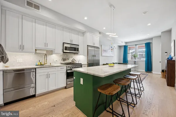 a kitchen that has a lot of cabinets in it and stainless steel appliances