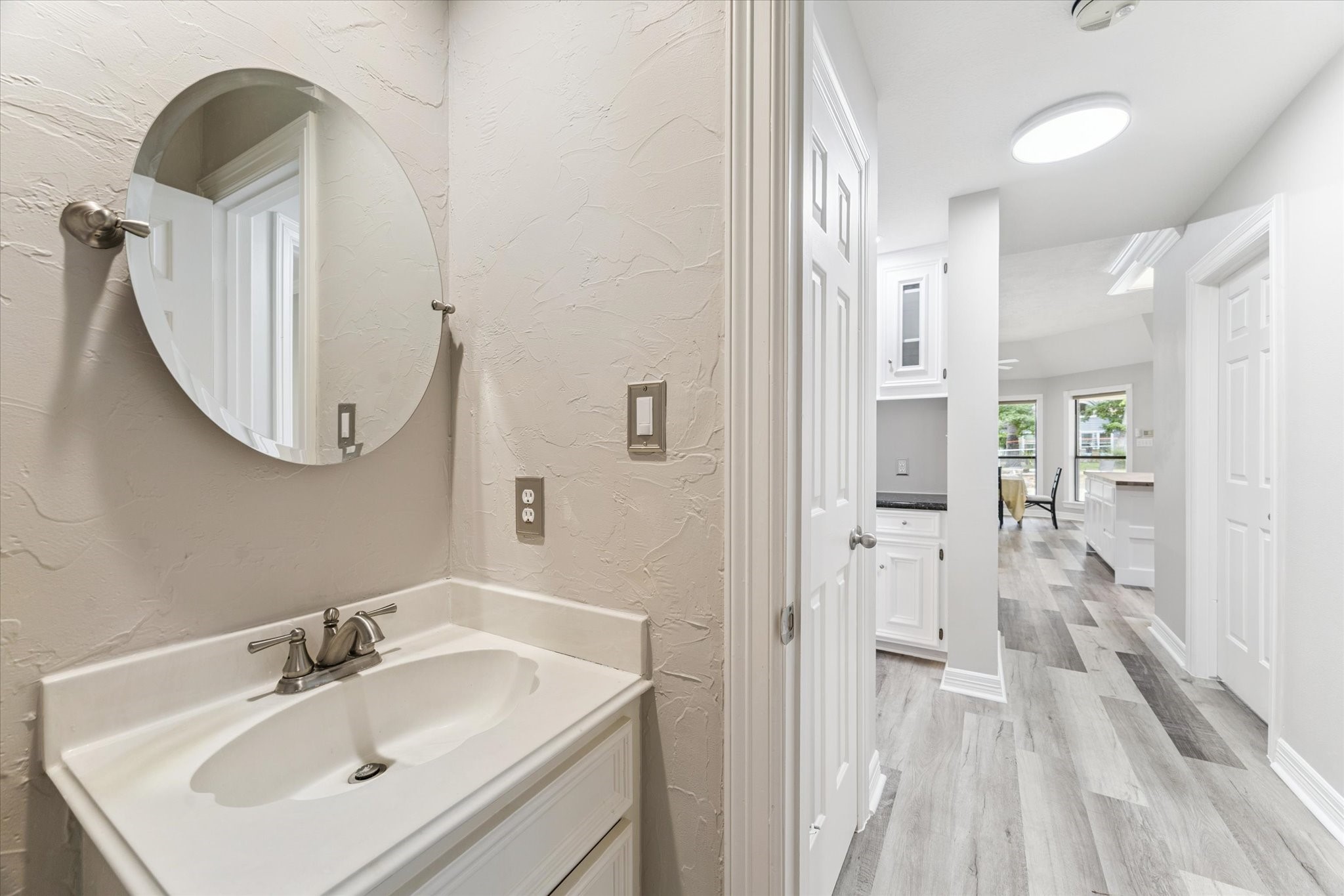 23818 Pin Oak Drive Spring, TX 77389 - Photo 20 of 31 Crisp and clean powder bath conveniently located for guests, featuring a modern round mirror and subtle texture on the walls.