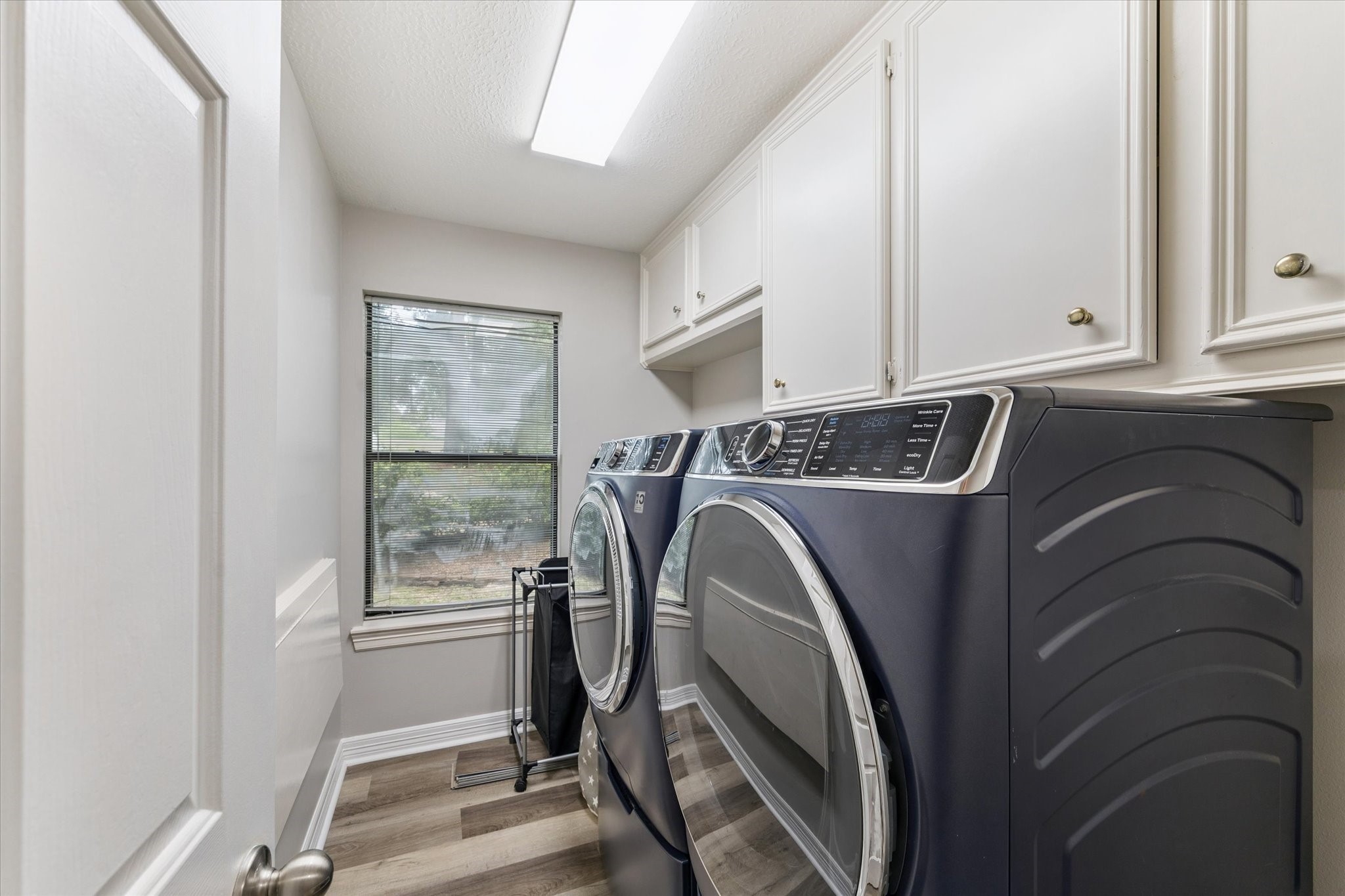 23818 Pin Oak Drive Spring, TX 77389 - Photo 29 of 31 Dedicated laundry room with full-size washer and dryer, upper cabinets for storage, and a window that brings in natural light.