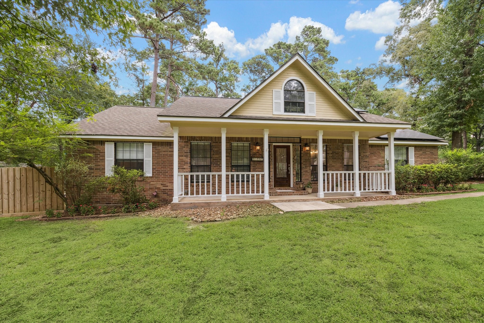 23818 Pin Oak Drive Spring, TX 77389 - Photo 30 of 31 Charming curb appeal with a wide front porch, classic brick façade, and dormer window detail, all nestled on a wooded lot.