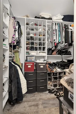a view of walk in closet with clothes and shoes