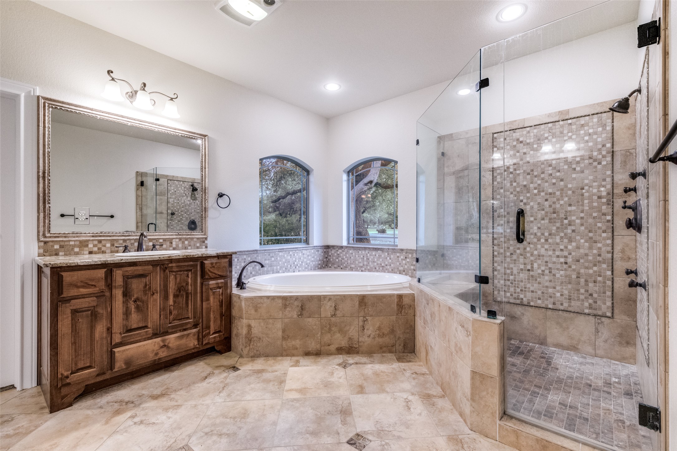 101 Copper Leaf Court Georgetown, TX 78633 - Photo 16 of 31 Spacious bathroom featuring a large soaking tub, walk-in shower with mosaic tile, wood-finish vanity with granite countertop, and tiled flooring
