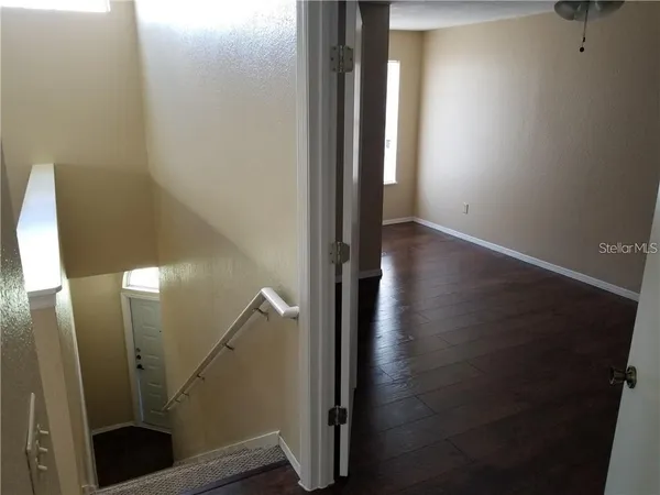 an empty room with wooden floor fan and windows