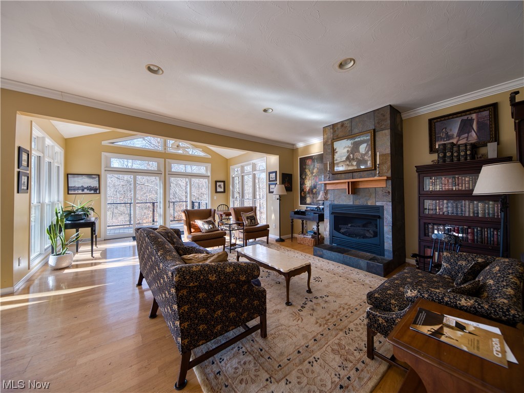 Living room featuring light wood-type flooring, crown molding, and a fireplace