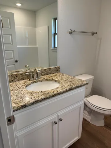 a bathroom with a granite countertop sink toilet and mirror