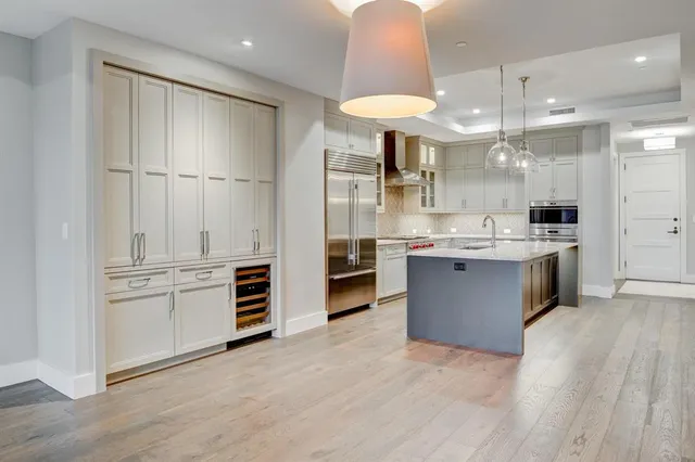 a large kitchen with stainless steel appliances kitchen island granite countertop a stove and a refrigerator