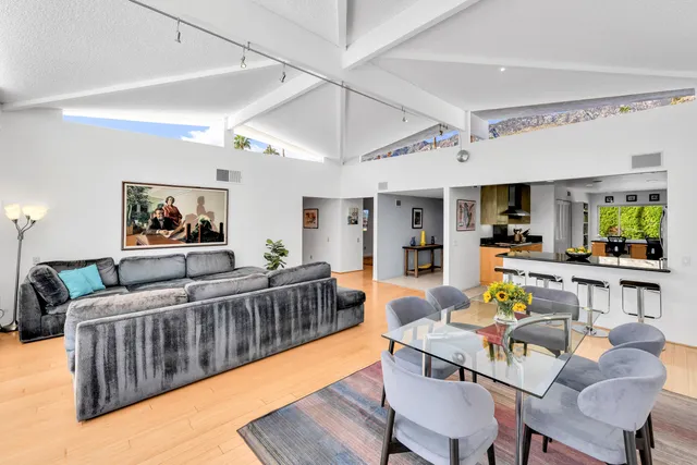 a living room with furniture kitchen view and a wooden floor