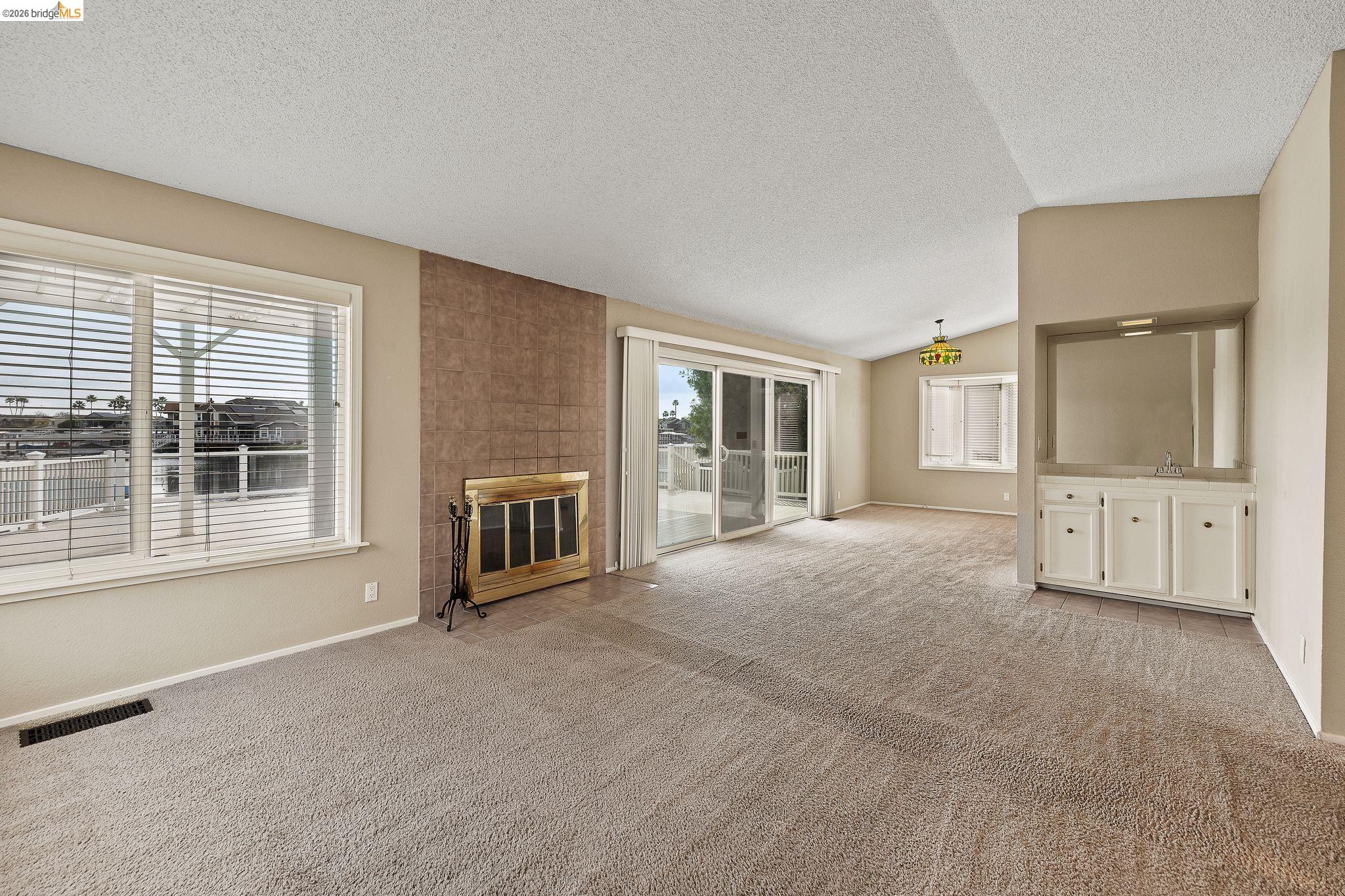 1147 Willow Lake Road Discovery Bay, CA 94505 - Photo 14 of 59 Unfurnished living room featuring light carpet, a fireplace, and healthy amount of natural light