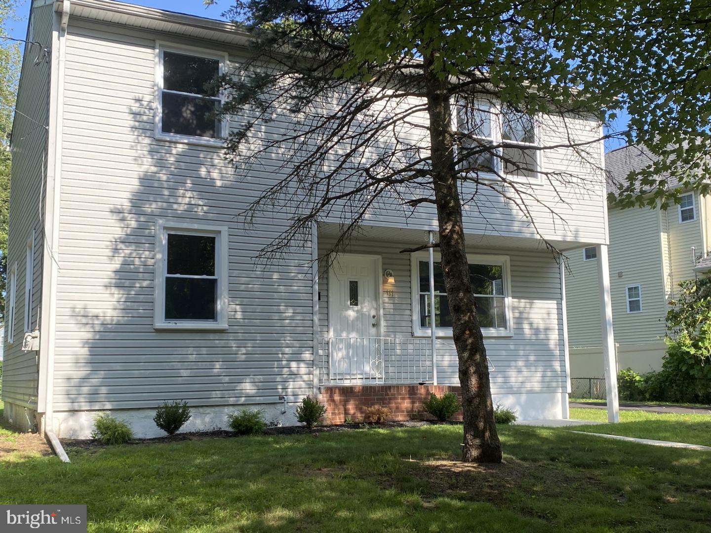 a front view of a house with a yard and a tree