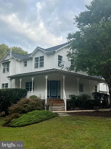 a front view of a house with a garden and trees