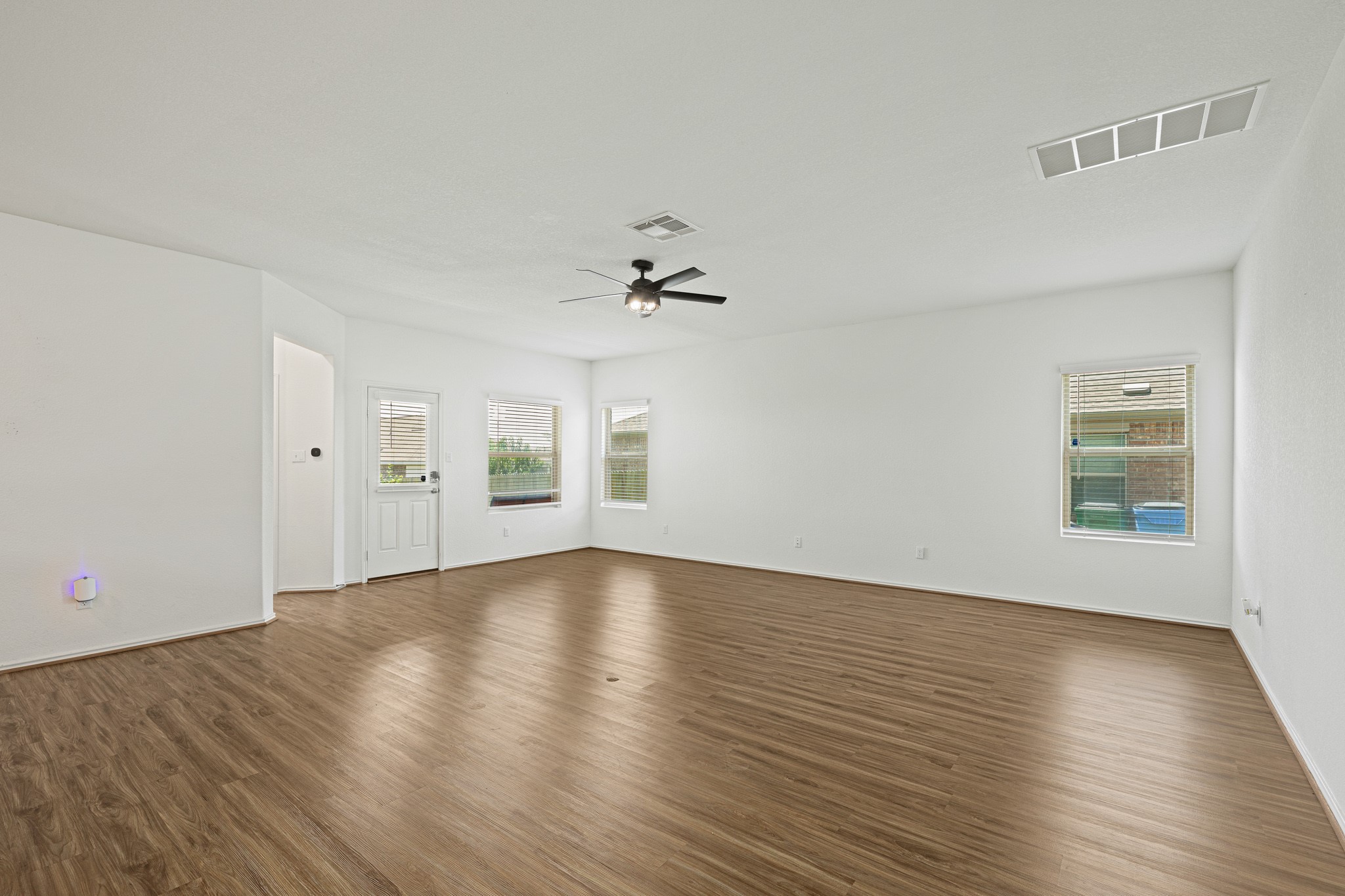21317 Resource Road Pflugerville, TX 78660 - Photo 6 of 37 A spacious living area features rich wood flooring and abundant natural light, creating an inviting atmosphere.