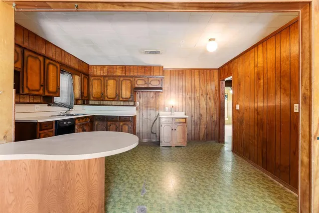 a kitchen with stainless steel appliances a dining table chairs sink and cabinets