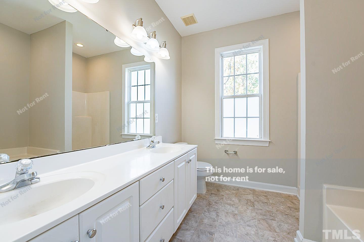 8909 Sauls Road Raleigh, NC 27603 - Photo 6 of 23 a spacious bathroom with a double vanity sink large mirror and a bathtub