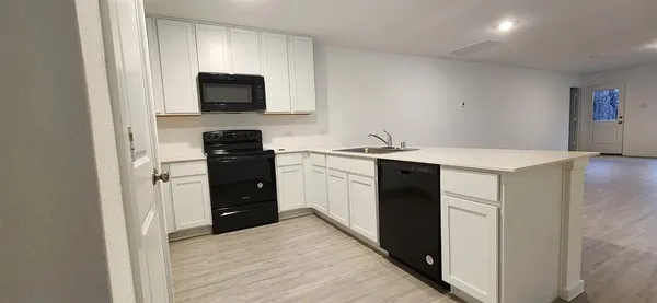 a kitchen with a sink and a stove top oven with wooden floor