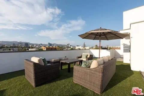 a view of a roof deck with couches under an umbrella