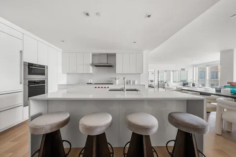 a kitchen with cabinets a sink dishwasher a stove and chairs with wooden floor