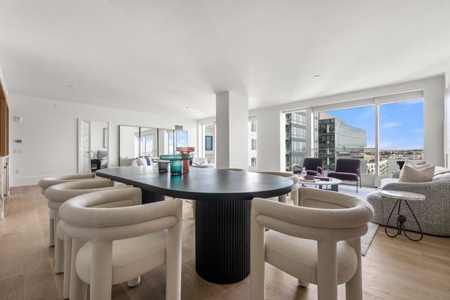 a living room with furniture a large window and kitchen view