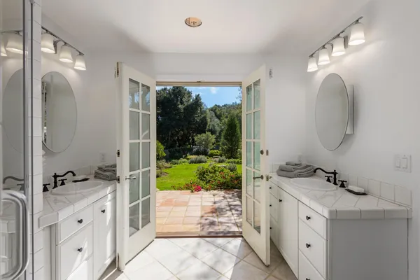 a spacious bathroom with a double vanity sink a mirror a bathtub and next to a window